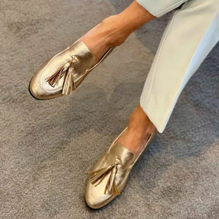 Women's metallic gold slip-on loafers with tassel detailing and low block heels