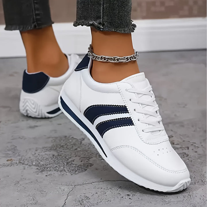 White women's lace-up sneakers with navy side stripes and round toes