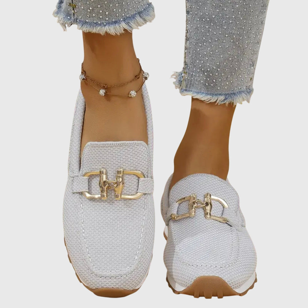 Women's textured slip-on sneakers with metallic buckle detail and flat ridged soles