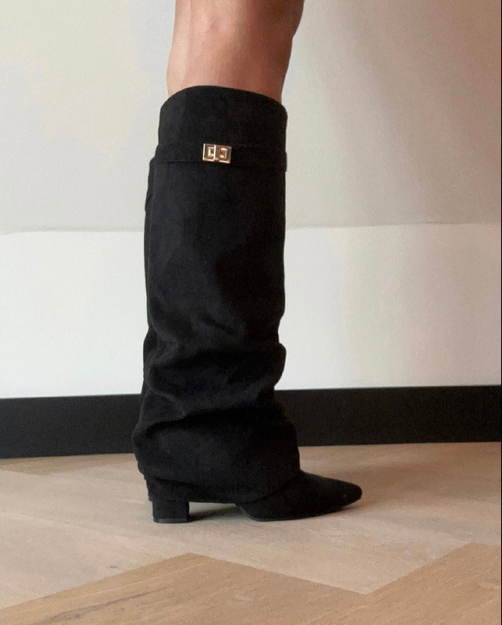Black slouch knee-high boots with pointed toes, low heels and buckle straps