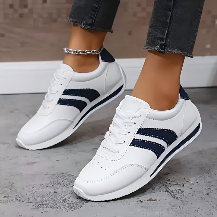 White women's lace-up sneakers with navy side stripes and round toes
