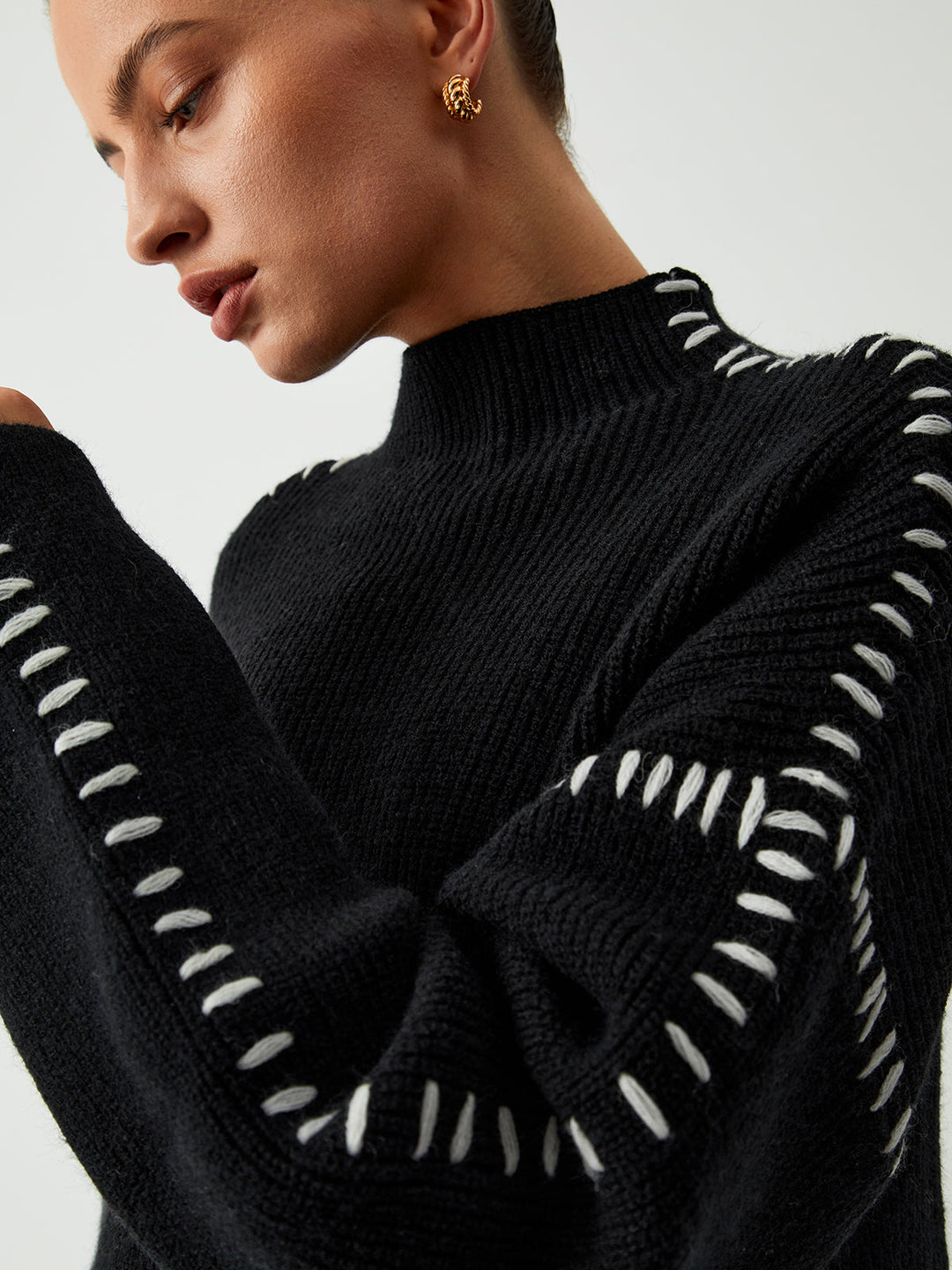 Women's black oversized knit sweater with contrast stitch seams and mock neck