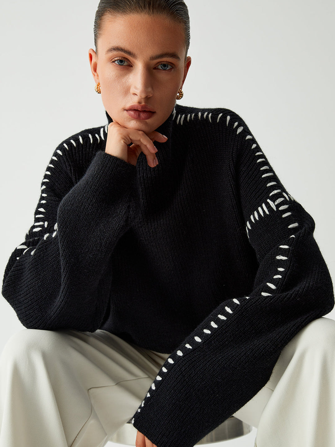 Women's black oversized knit sweater with contrast stitch seams and mock neck