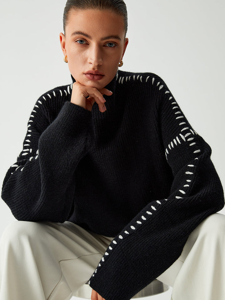 Women's black oversized knit sweater with contrast stitch seams and mock neck