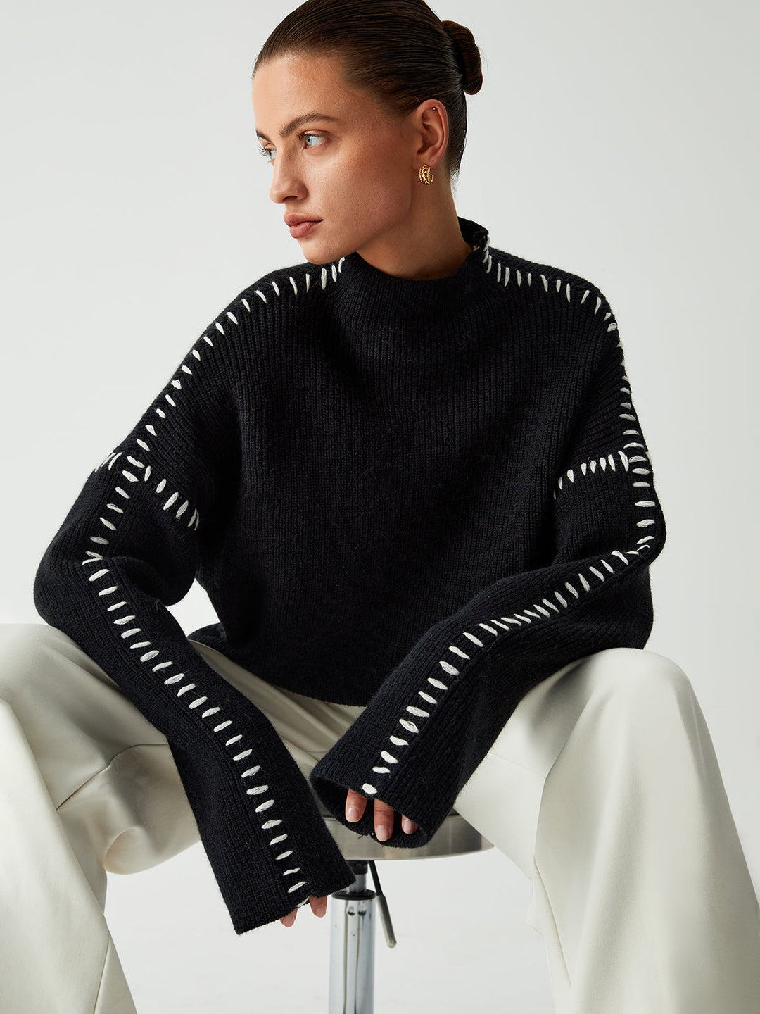 Women's black oversized knit sweater with contrast stitch seams and mock neck