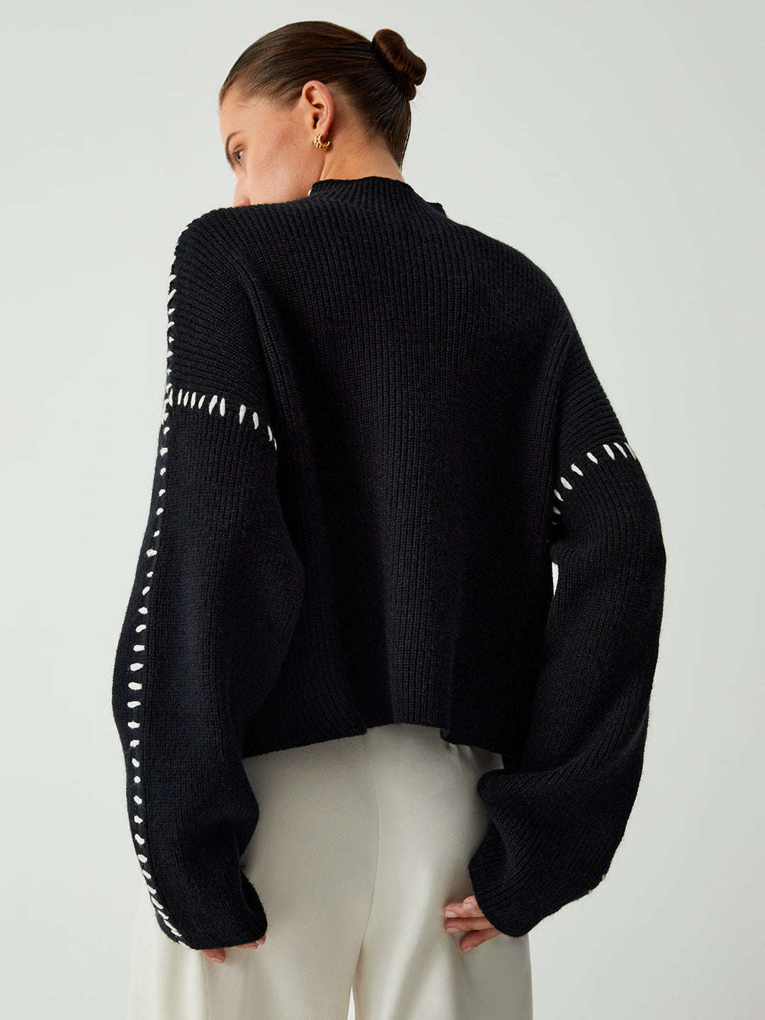 Women's black oversized knit sweater with contrast stitch seams and mock neck