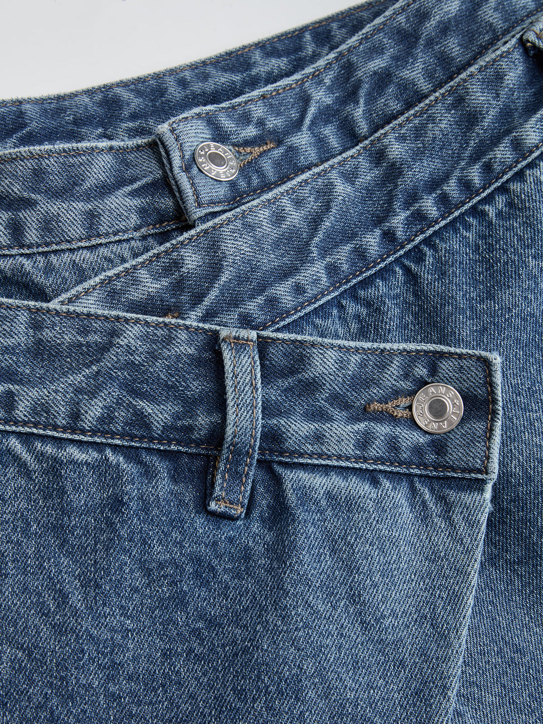Women's blue wide-leg jeans with cross-front button waistband and utility pocket