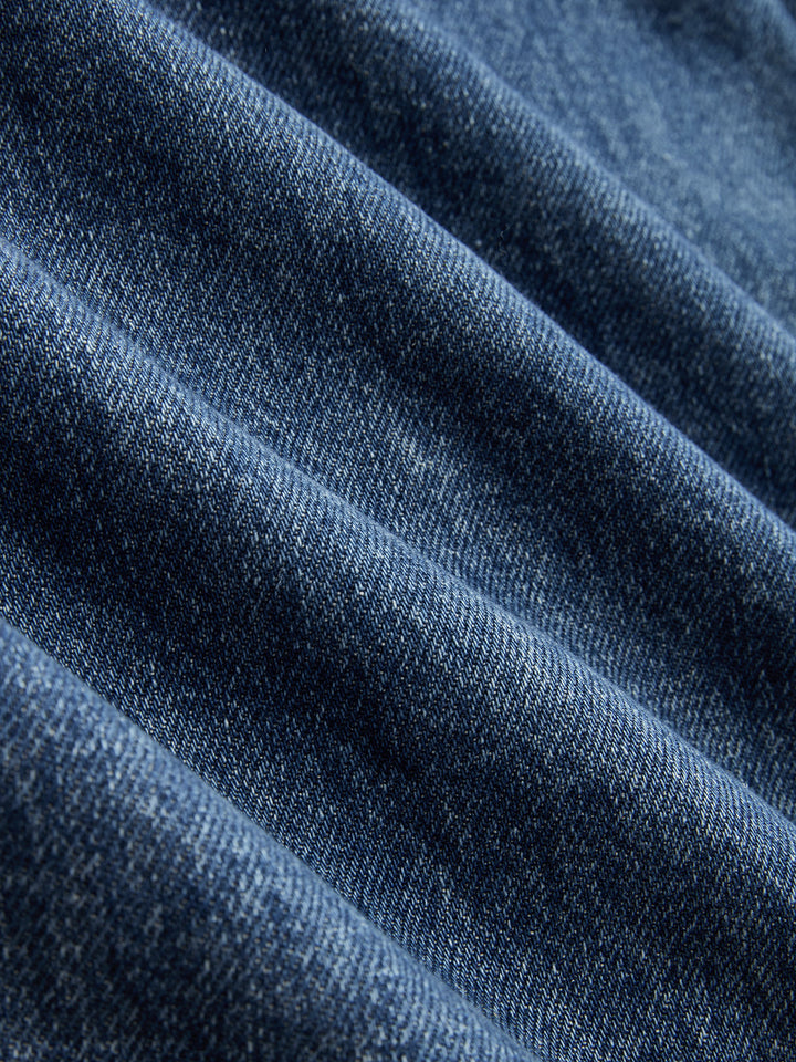 Women's blue wide-leg jeans with cross-front button waistband and utility pocket