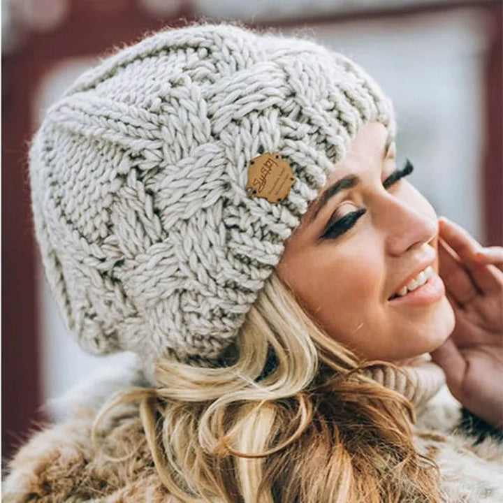 Women's cable knit beanie hat with rolled cuff and front patch