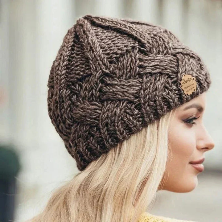 Women's cable knit beanie hat with rolled cuff and front patch