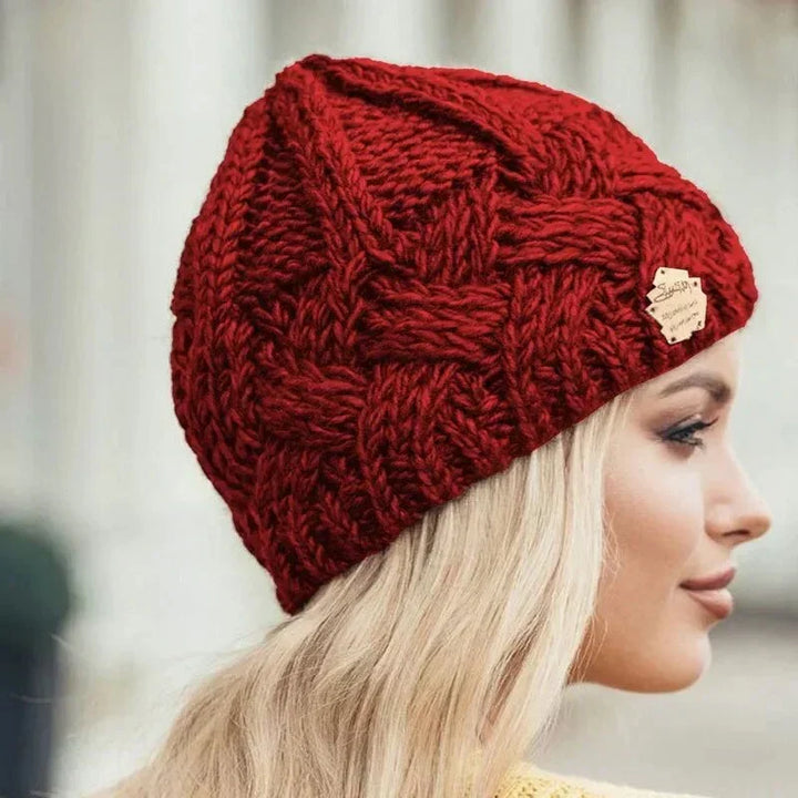 Women's cable knit beanie hat with rolled cuff and front patch