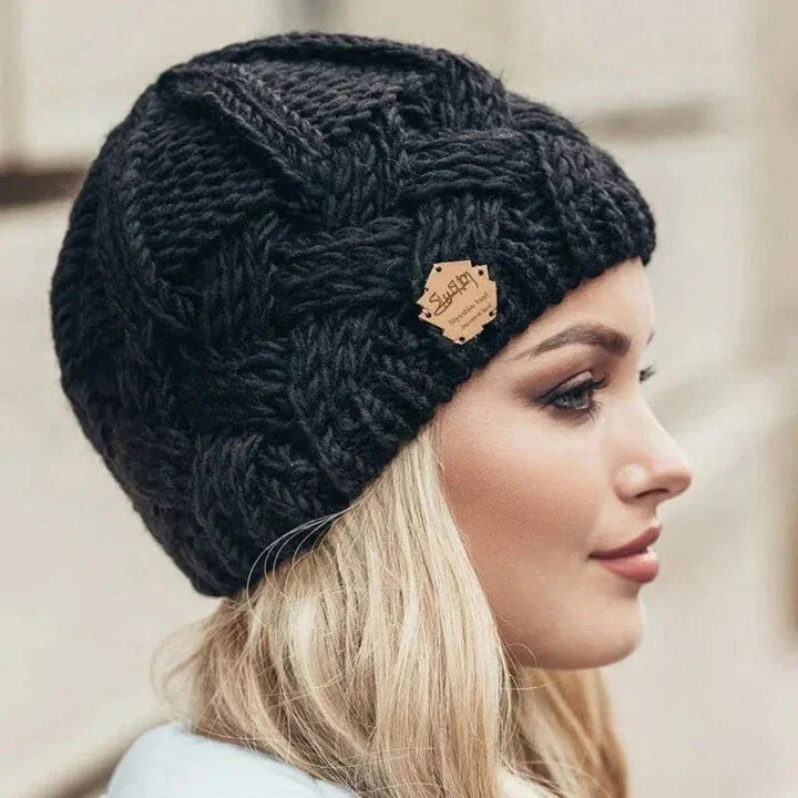 Women's cable knit beanie hat with rolled cuff and front patch