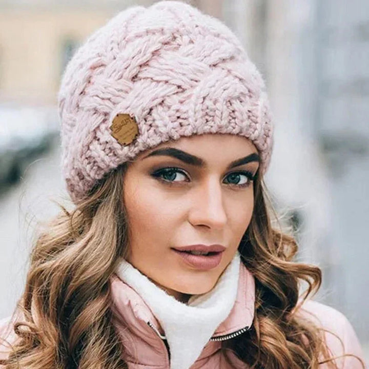 Women's cable knit beanie hat with rolled cuff and front patch