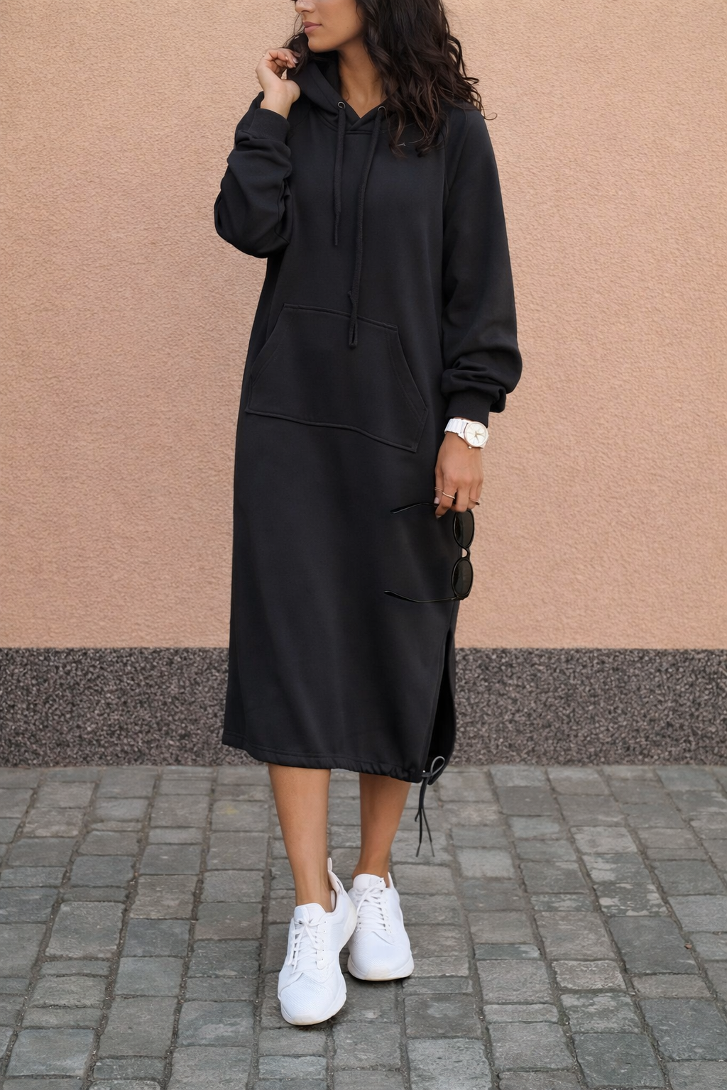 Woman wearing a long hooded sweatshirt midi dress with a front pouch pocket and side hem drawstrings