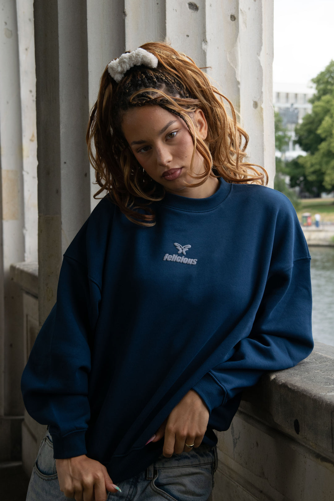 Women's navy crewneck sweatshirt with raised chest logo and long sleeves