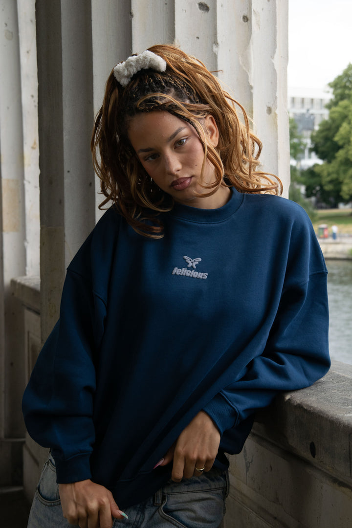 Women's navy crewneck sweatshirt with raised chest logo and long sleeves