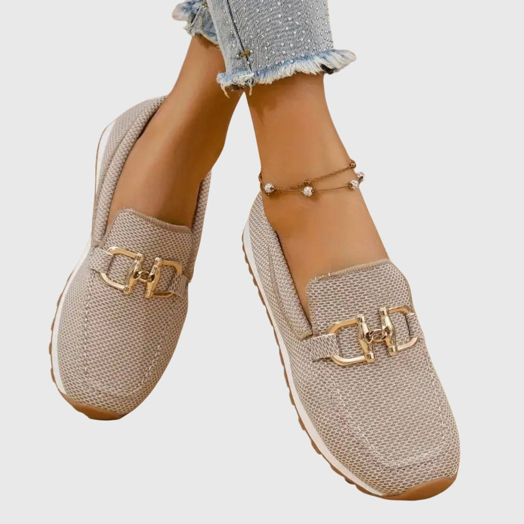 Women's textured slip-on sneakers with metallic buckle detail and flat ridged soles