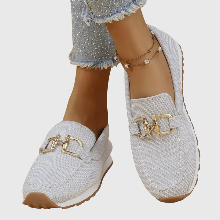 Women's textured slip-on sneakers with metallic buckle detail and flat ridged soles