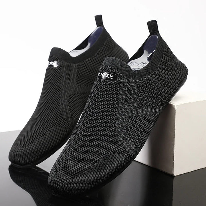 Knit slip-on shoes with round toes, pull tabs and flat black soles