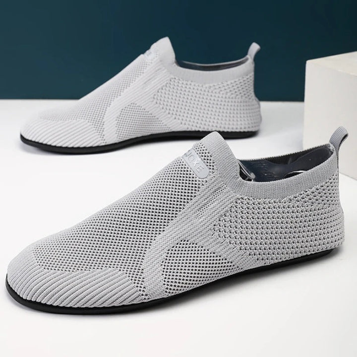 Knit slip-on shoes with round toes, pull tabs and flat black soles
