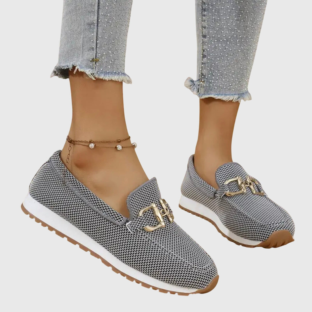 Women's textured slip-on sneakers with metallic buckle detail and flat ridged soles