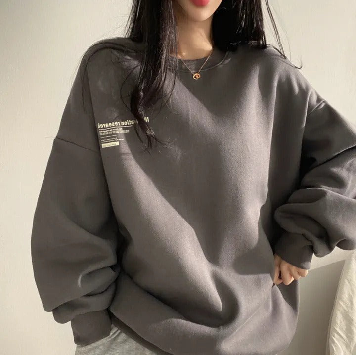 Women's oversized crewneck sweatshirt with long sleeves and a small text graphic