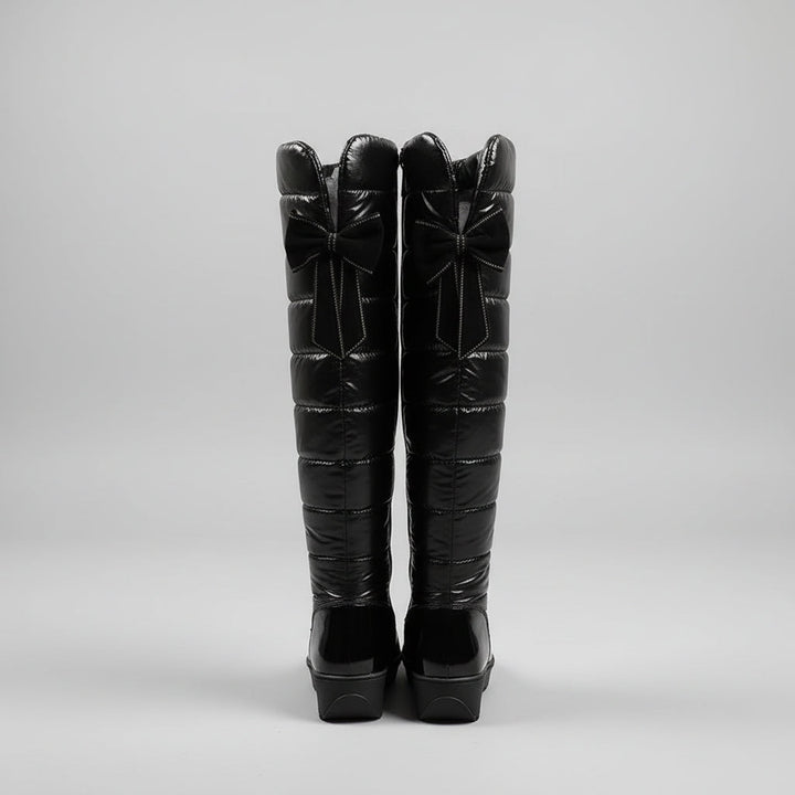 Women's black quilted over-the-knee boots with round toes, flat platform soles and bow detail