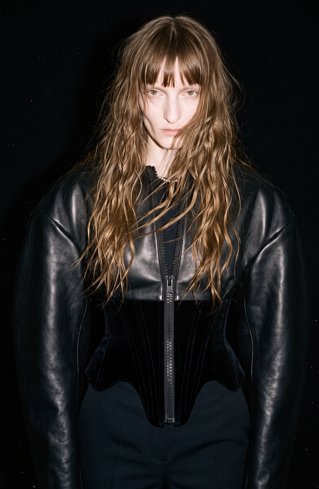 Black women's corset jacket with glossy upper panels, long sleeves and a front zipper