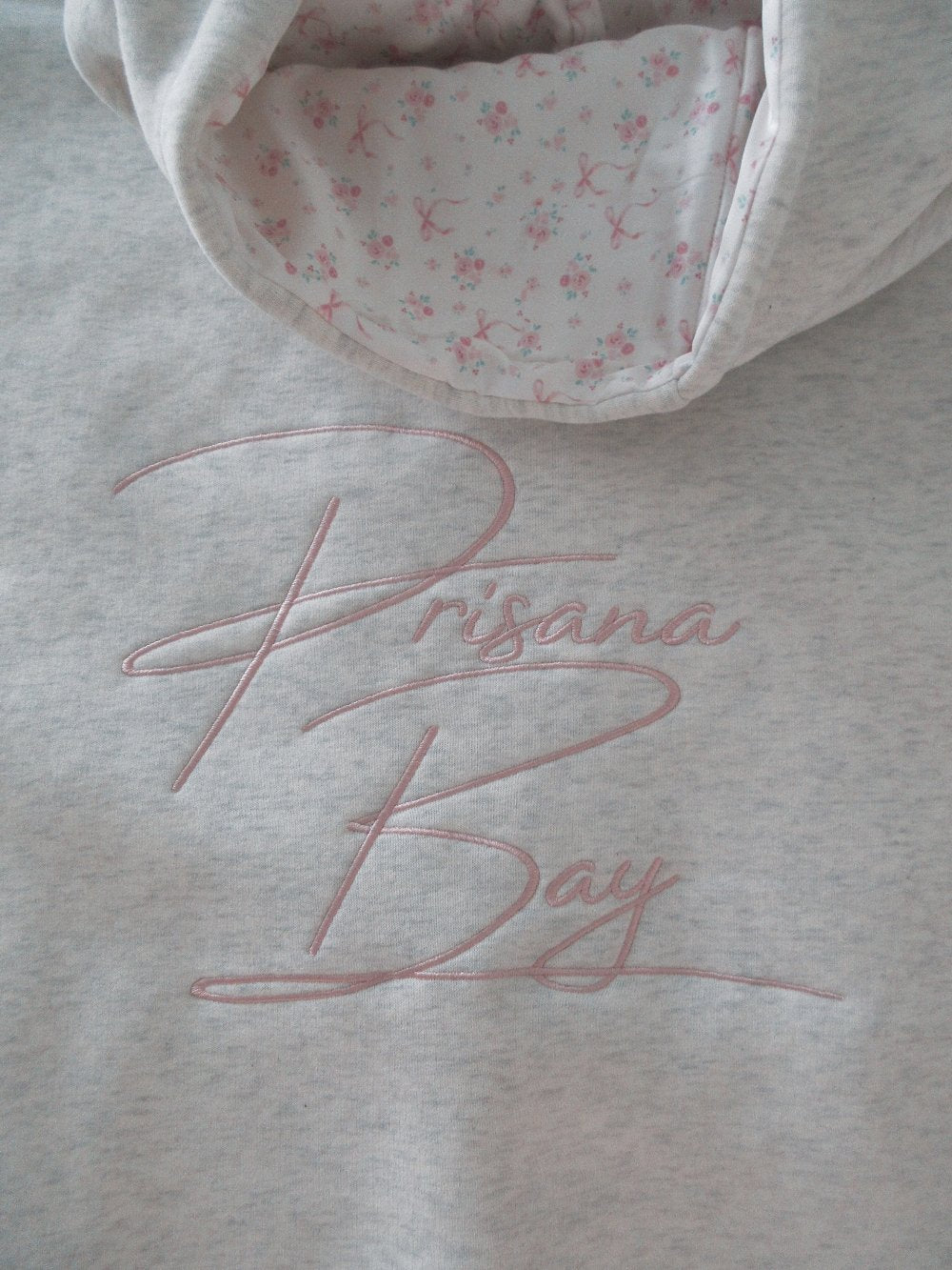 Light grey women's hoodie with floral lined hood and pink embroidery