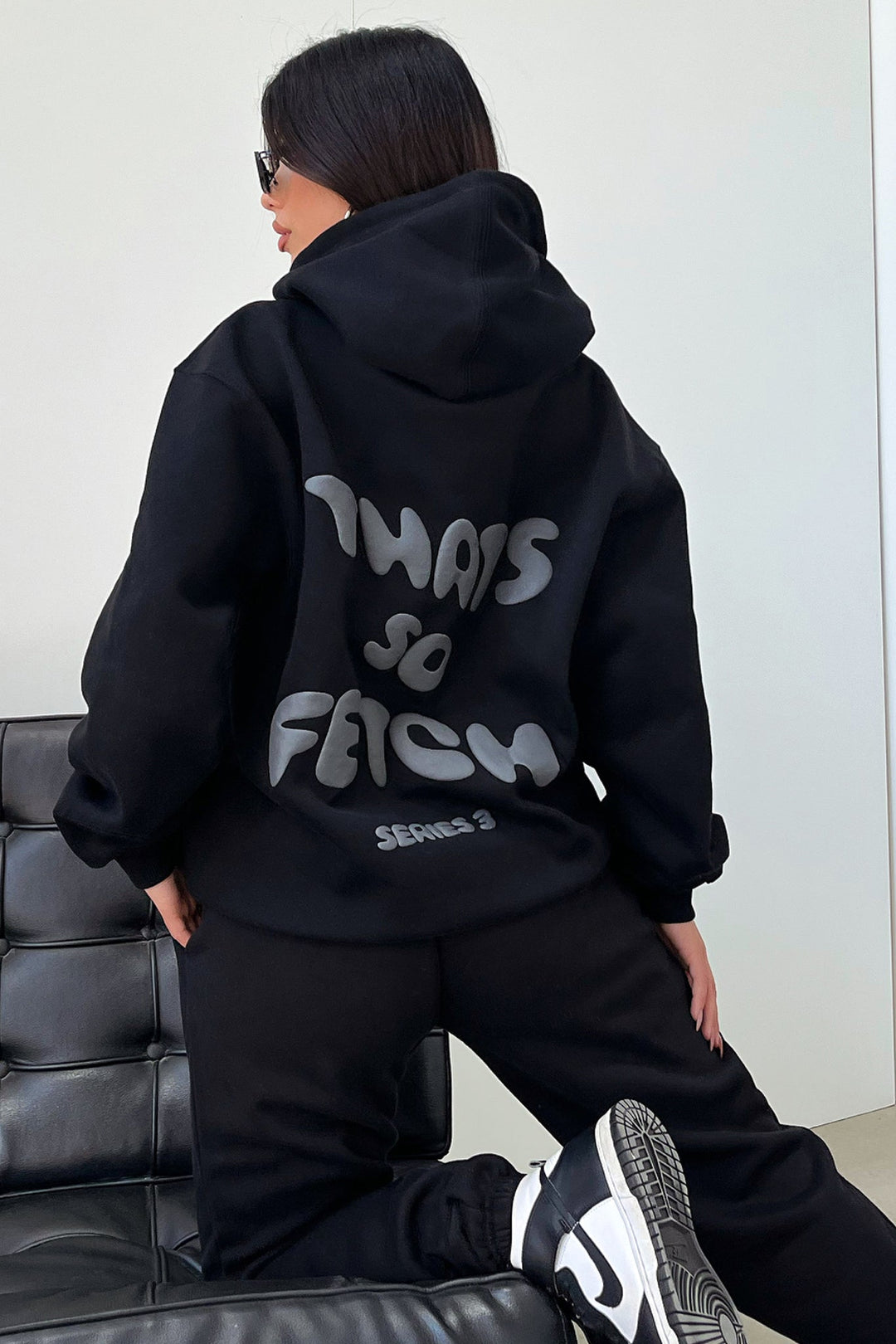 Women's black hooded sweatshirt with contrasting text graphic on the back