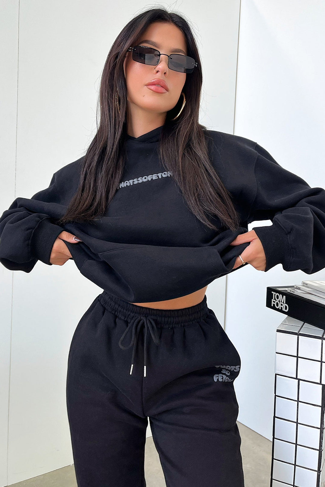 Women's black hooded sweatshirt with contrasting text graphic on the back