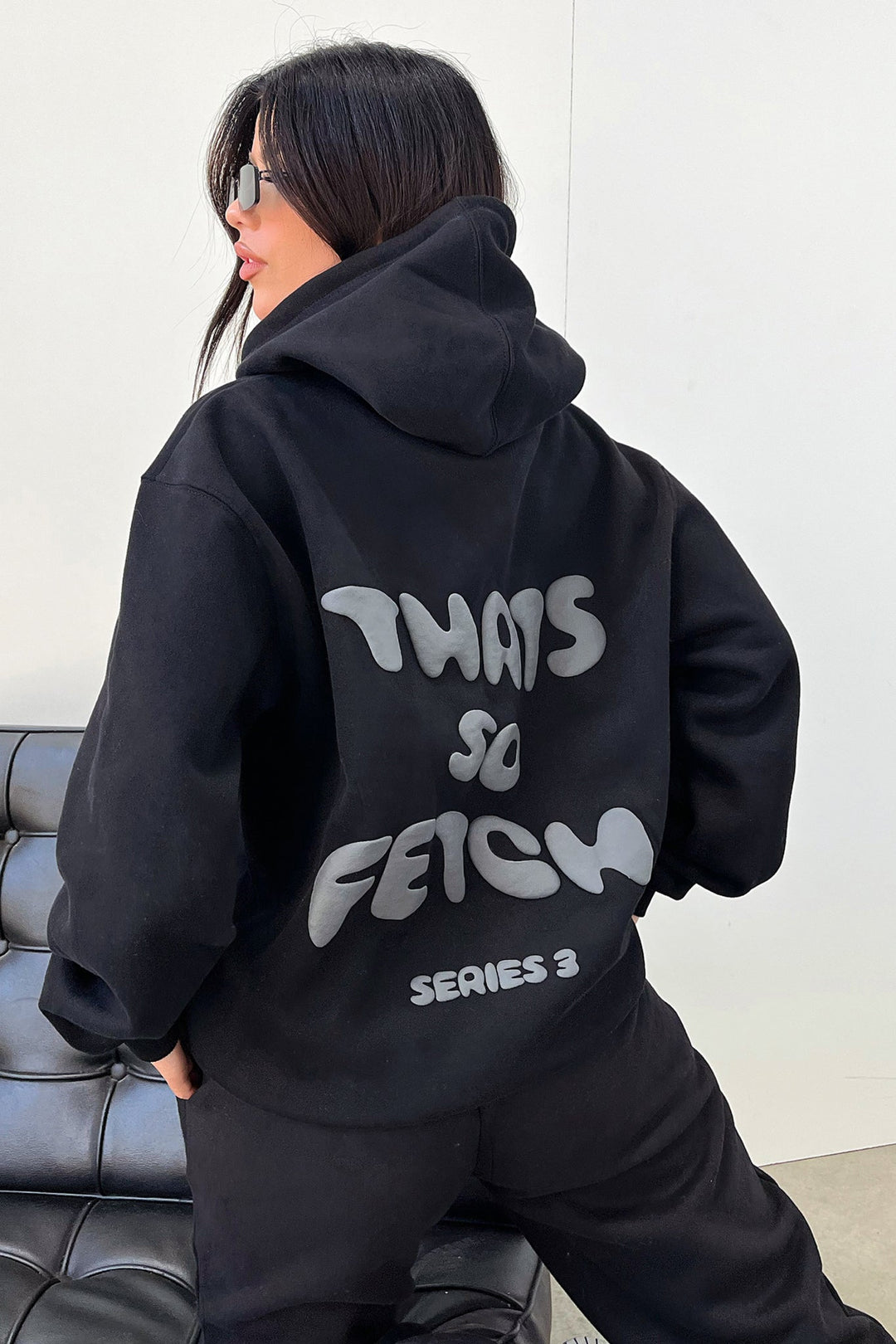 Women's black hooded sweatshirt with contrasting text graphic on the back
