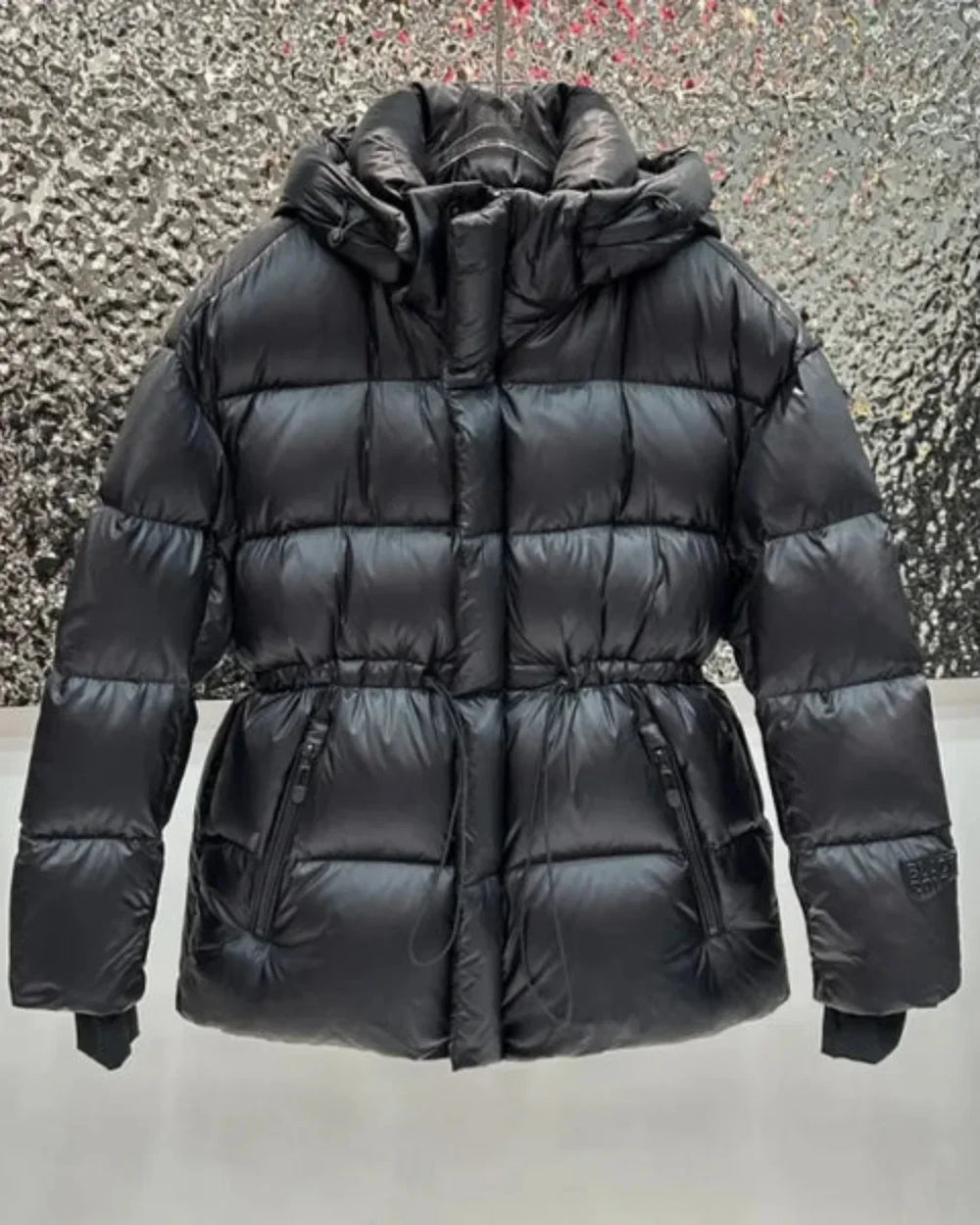 Women's black quilted hooded puffer jacket with adjustable waist and zip pockets