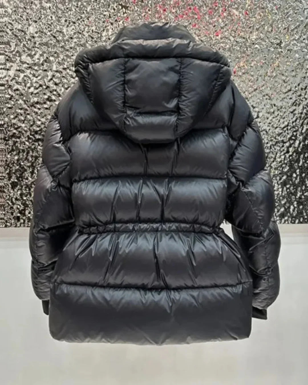 Women's black quilted hooded puffer jacket with adjustable waist and zip pockets